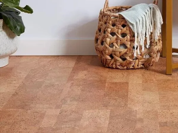 Warm tan cork flooring beside a woven basket with a white throw blanket and a potted plant.